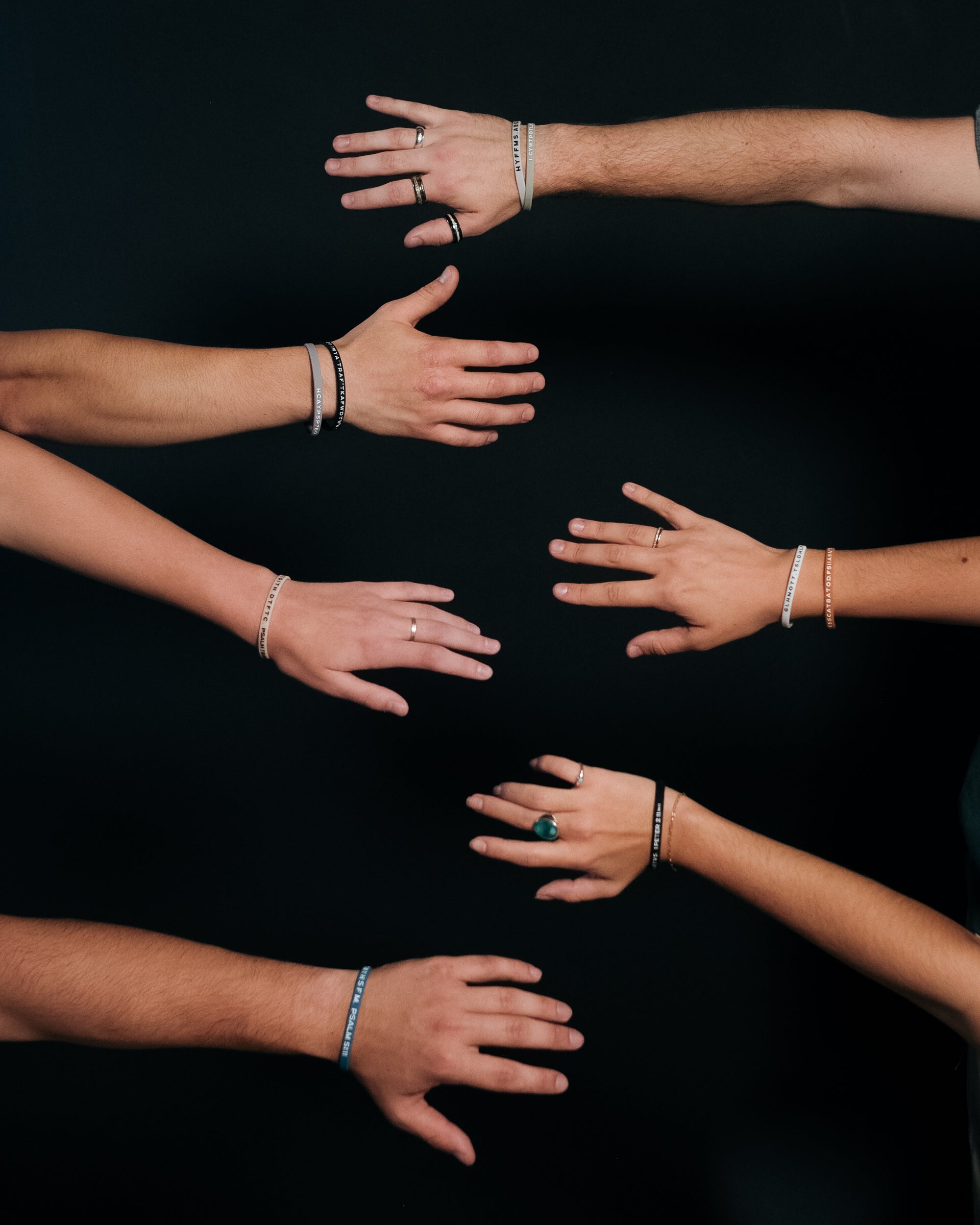 Six hands with Bible Memory Project wristbands reaching toward eachother